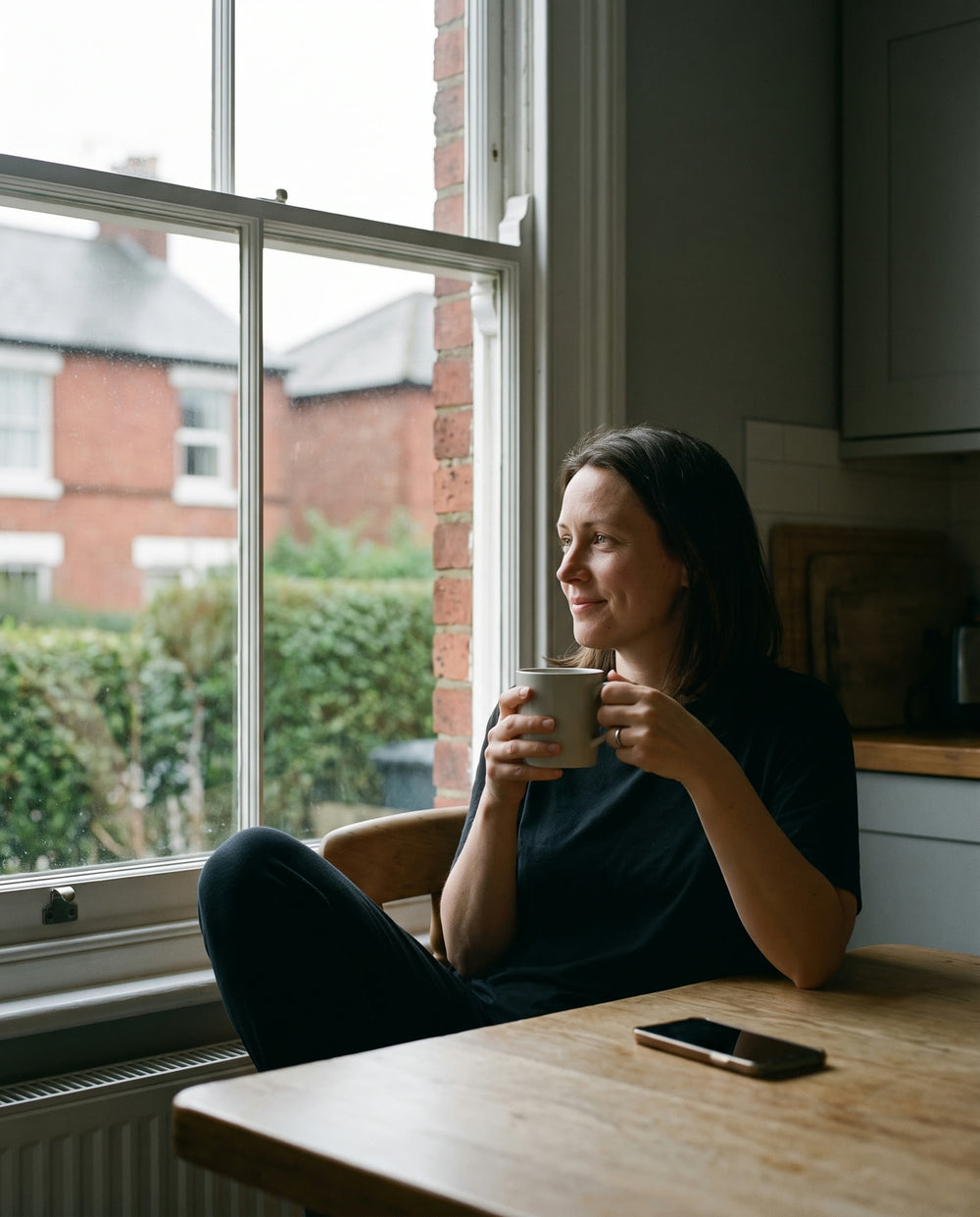 A mother relaxed at her kitchen table with her phone face down